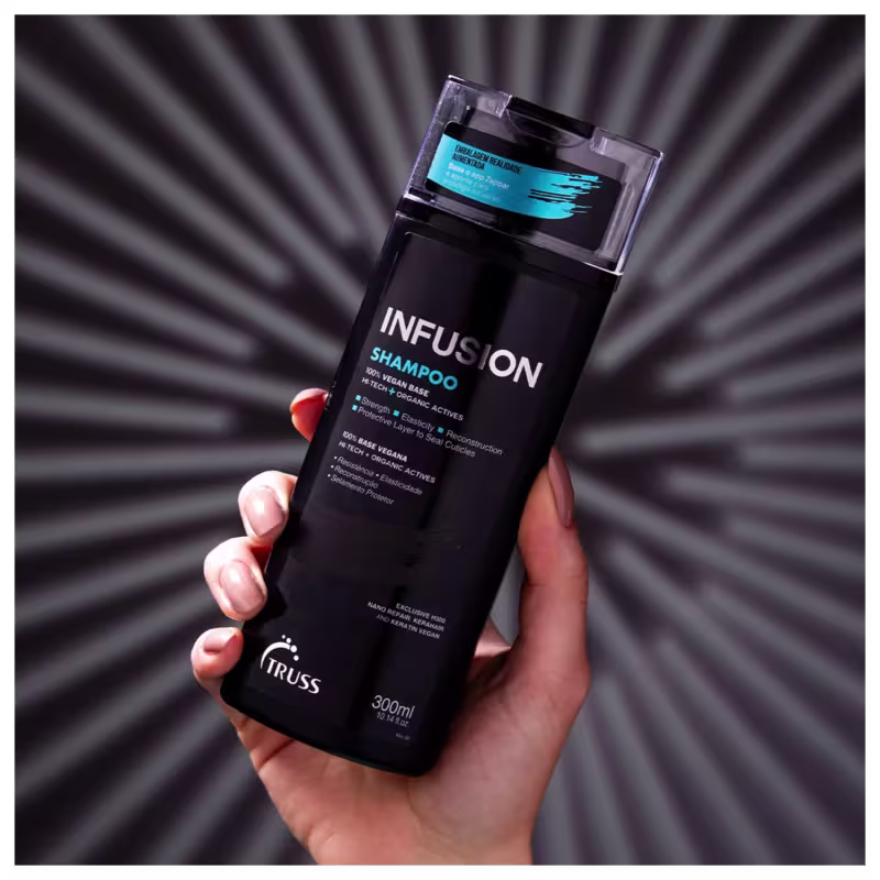 A imagem mostra uma mão segurando um frasco de shampoo da marca TRUSS. O frasco é preto e tem o nome "Infusion Shampoo" escrito nele. A imagem tem um fundo de linhas radiais cinza, dando destaque ao frasco de shampoo.