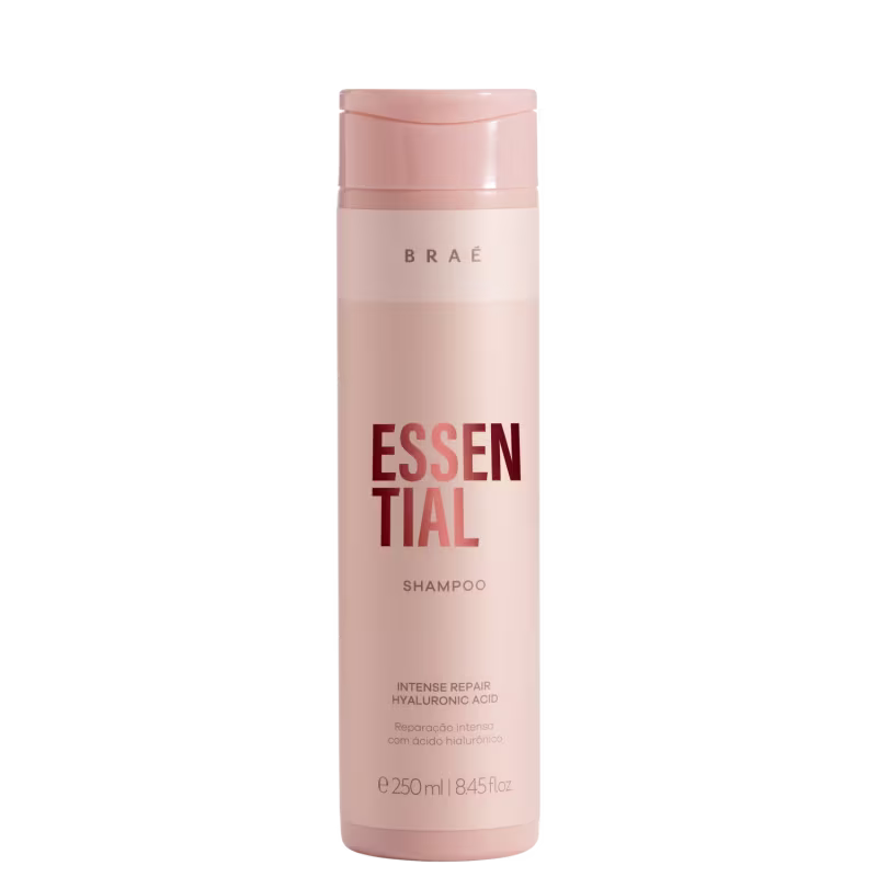 Shampoo Essential da marca Brae. Embalagem cilíndrica de plástico rígido na cor rosa claro. Rótulo com o nome do produto "Essential" em letras grandes e vermelhas, e a palavra "Shampoo" abaixo em letras menores.