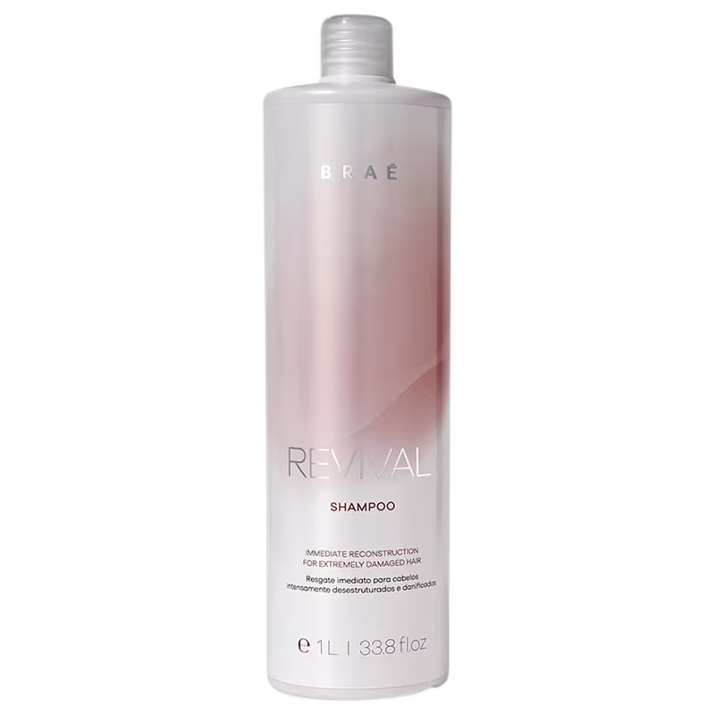 Shampoo Revival da marca Braé em embalagem plástica transparente com formato cilíndrico. A embalagem é predominantemente branca na parte superior e rosa claro degradê na parte inferior.