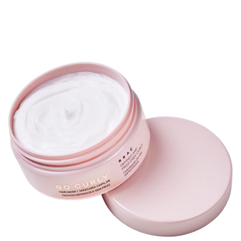 Máscara capilar em embalagem plástica rosa claro. A embalagem é redonda com tampa removível. O produto é branco e cremoso.
