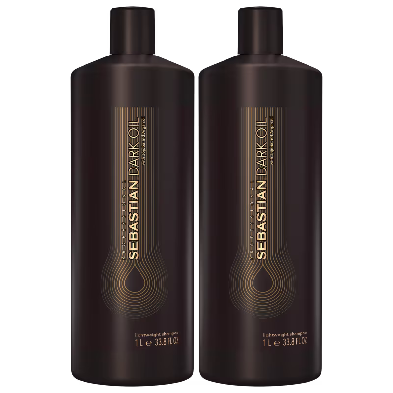 São dois frascos de shampoo leve da marca Sebastian Professional. Os frascos são de plástico marrom escuro e têm formato cilíndrico com tampa preta. Na parte frontal, há o logotipo e nome da marca "Sebastian Dark Oil" em letras douradas.