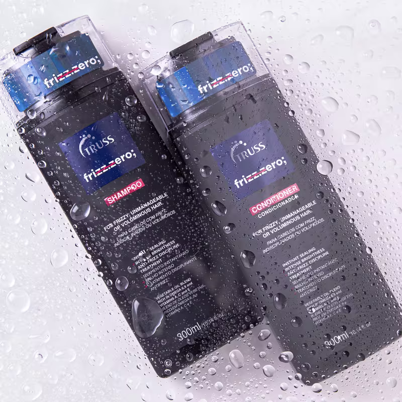 Produtos de cuidados capilares Truss frizz-Zero em embalagens plásticas transparentes. Rótulos pretos com detalhes em vermelho, incluindo os nomes dos produtos "Shampoo" e "Condicionador" e descrições como "Para cabelos lisos e macios".