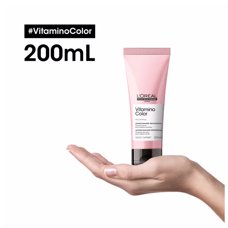 Produto capilar da linha Vitamino Color da L'Oréal Professionnel. Embalagem em tubo plástico rosa de 200ml. Rótulo preto com o nome do produto e detalhes em espanhol. Uma mão feminina segura o tubo.