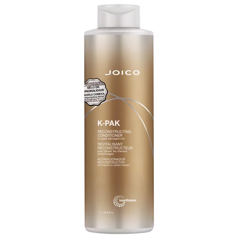 Condicionador reconstrutivo K-Pak da Joico para reparar cabelos danificados. Embalagem plástica cilíndrica branca e dourada. Rótulo com o nome do produto "K-PAK Reconstructing Conditioner" em letras grandes.