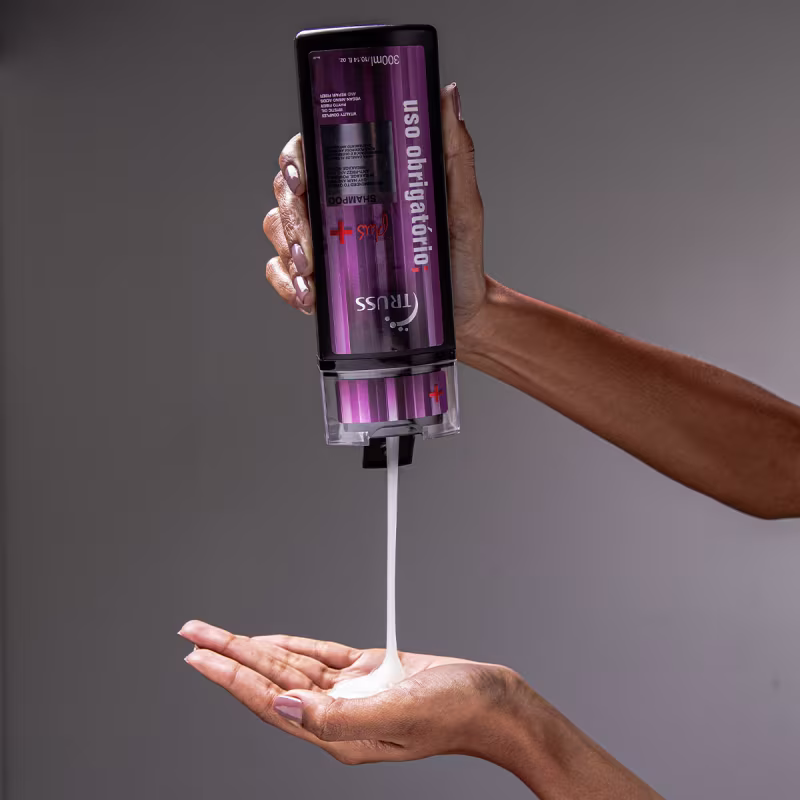 A imagem mostra uma mão despejando shampoo na outra mão. É possível ver a textura viscosa do produto.