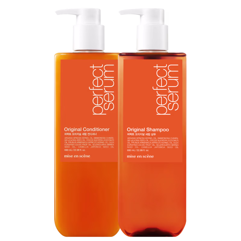 Dois frascos de plástico laranja com bombas brancas, contendo Shampoo Original e Condicionador Original da marca Mise en Scène. Os rótulos exibem informações sobre os ingredientes e a marca.