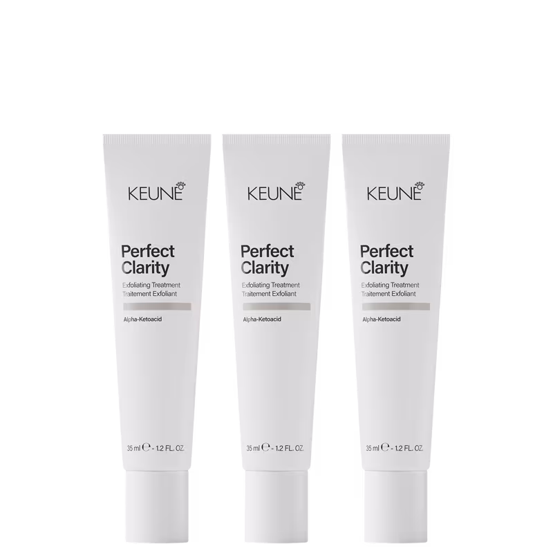 Três tubos brancos da linha Keune Perfect Clarity, um tratamento esfoliante com ácido alfa-cetoacídico. Cada tubo contém 35 ml do produto e apresenta o nome da linha e do ingrediente ativo em destaque.
