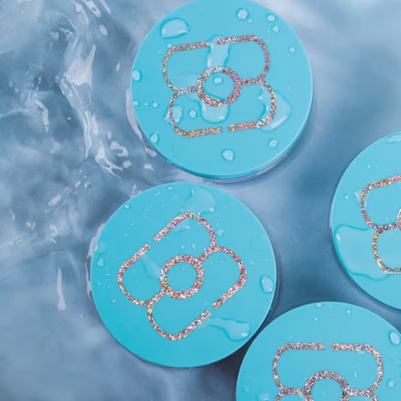 O produto apresentado é um pó hidratante facial de tapioca. Ele vem embalado em pequenos compactos redondos de cor azul clara.