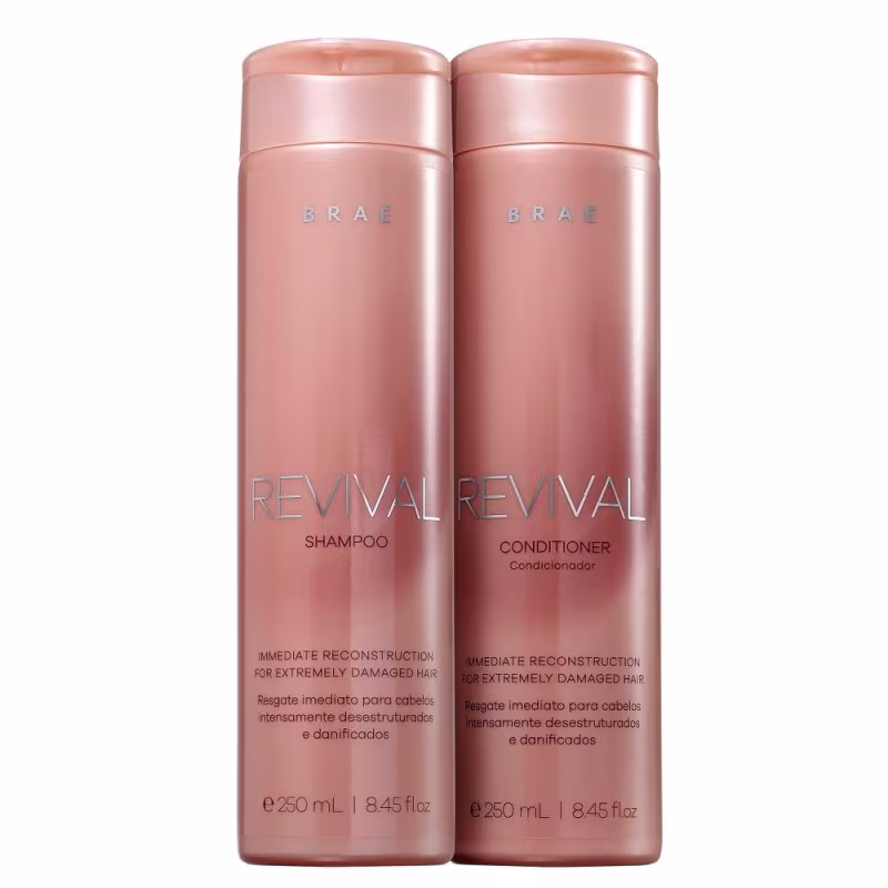 Dois frascos de plástico rígido na cor rosa metálico, contendo shampoo e condicionador da linha Revival da marca Brae. Os frascos têm formato cilíndrico e tampa rosqueável na mesma tonalidade.