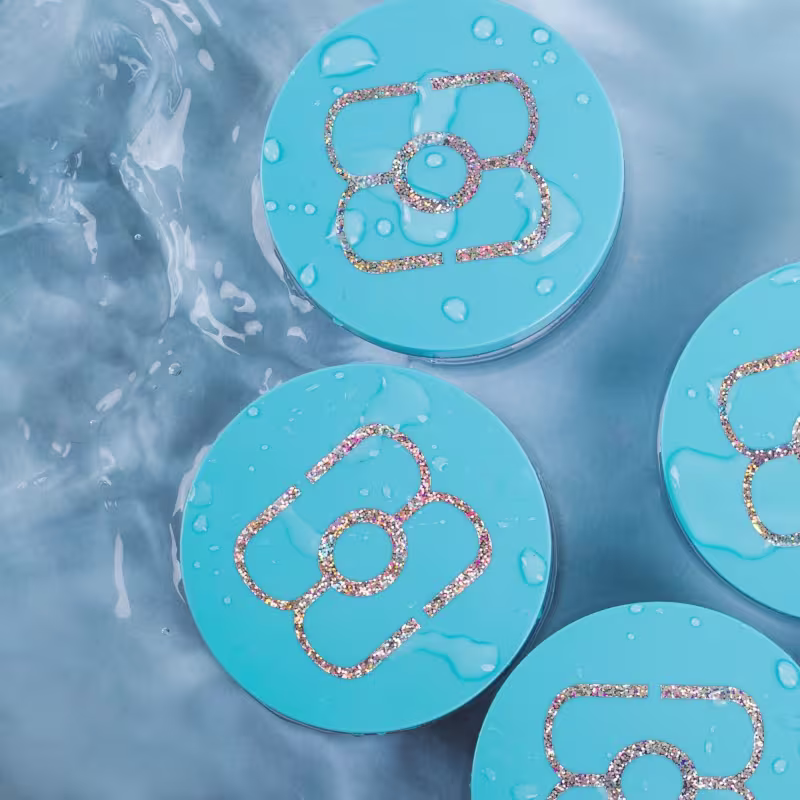 O produto apresentado é um pó hidratante facial de tapioca. Ele vem embalado em pequenos compactos redondos de cor azul clara.