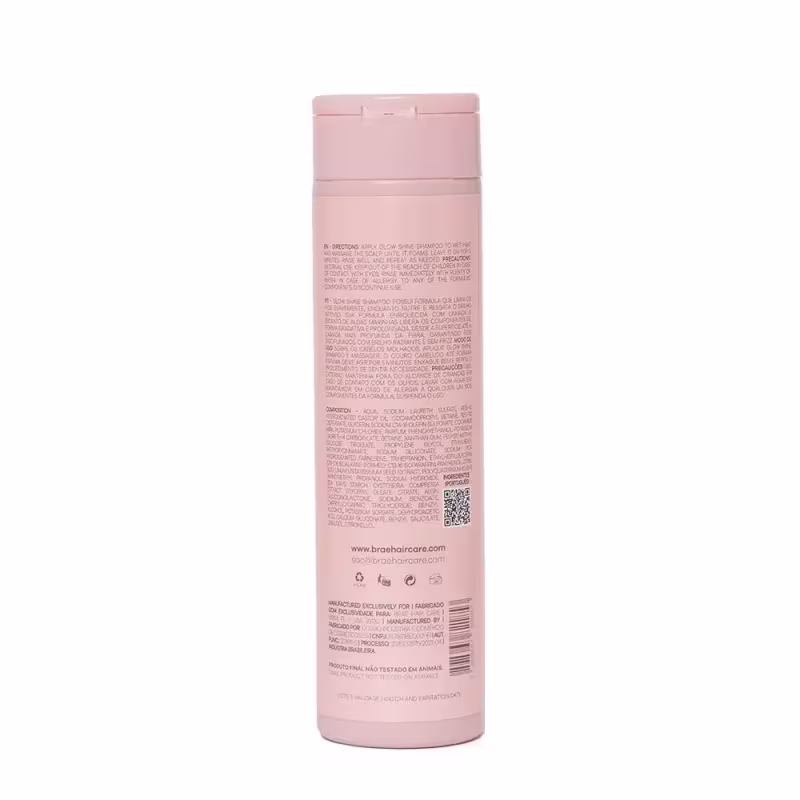Imagem mostra o verso do produto de cuidado capilar da marca Brae Hair Care. Embalagem plástica cilíndrica na cor rosa claro. Rótulo na parte frontal e traseira com informações do produto em texto preto, incluindo ingredientes, instruções de uso.