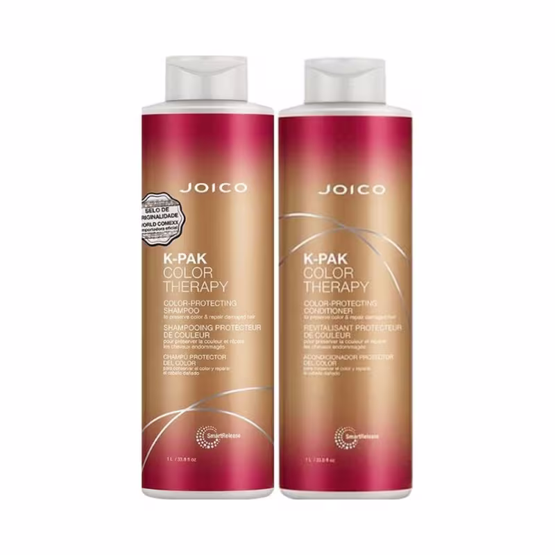 São frascos de shampoo e condicionador de 1 litro da linha K-Pak Color Therapy da marca Joico. Os frascos têm formato cilíndrico e tampas brancas. As embalagens apresentam uma combinação de cores com vermelho, dourado e branco.