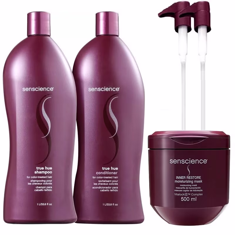 A imagem mostra dois frascos grandes de plástico vinho contendo shampoo e condicionador, além de um pote redondo de plástico roxo com máscara capilar. Ao fundo duas válvulas pump com a parte de cima no mesmo tom dos frascos.