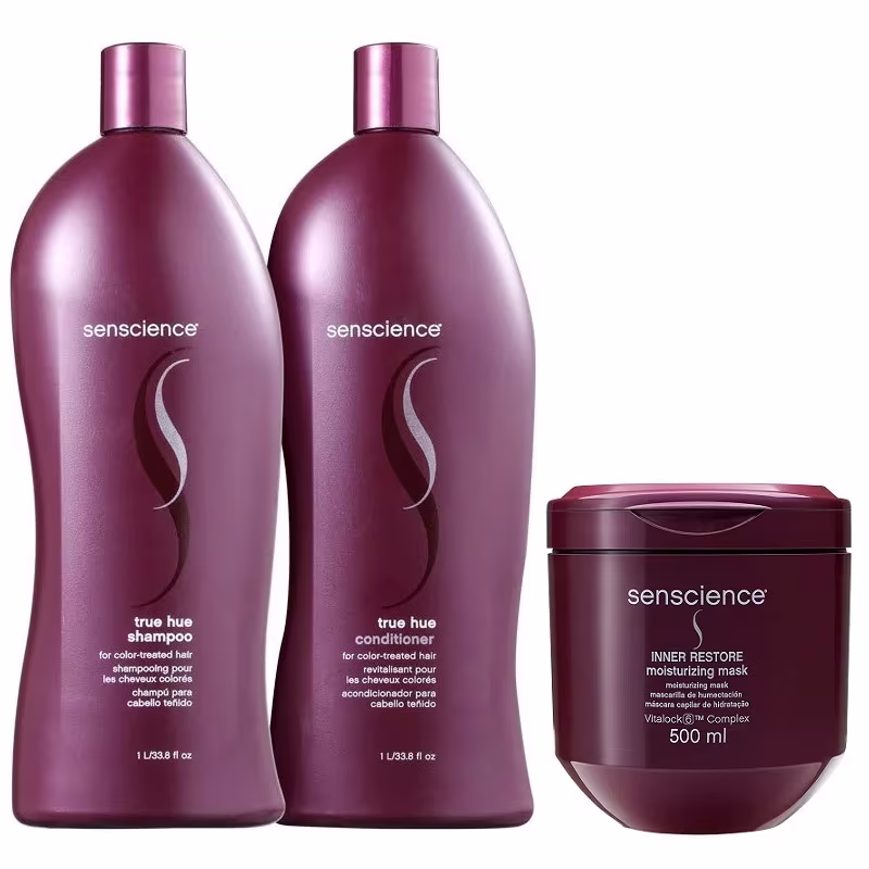 A imagem mostra dois frascos grandes de plástico vinho contendo shampoo e condicionador, além de um pote redondo de plástico roxo com máscara capilar. Os rótulos exibem o nome da marca, descrições dos produtos e instruções.
