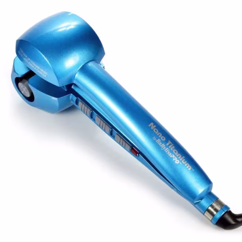 A imagem mostra o Modelador de Cachos da marca BaByliss Pro. O produto tem um design alongado e aerodinâmico na cor azul metálica brilhante. Possui uma cabeça arredondada com aberturas de ventilação e um cabo ergonômico preto na extremidade inferior.