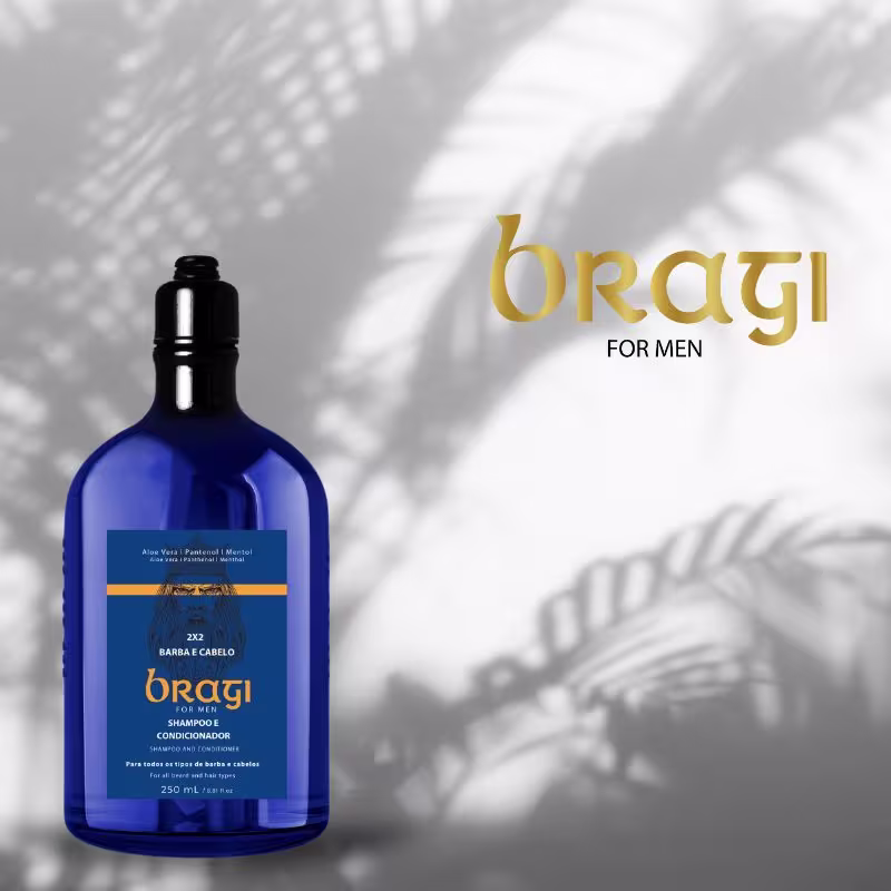 A imagem mostra a embalagem azul escura em formato de garrafa. O logotipo da marca Bragi, escrito em letras douradas, também está visível na imagem. Ao fundo aparece uma parede com sombras de ramos que parecem ser de uma palmeira.