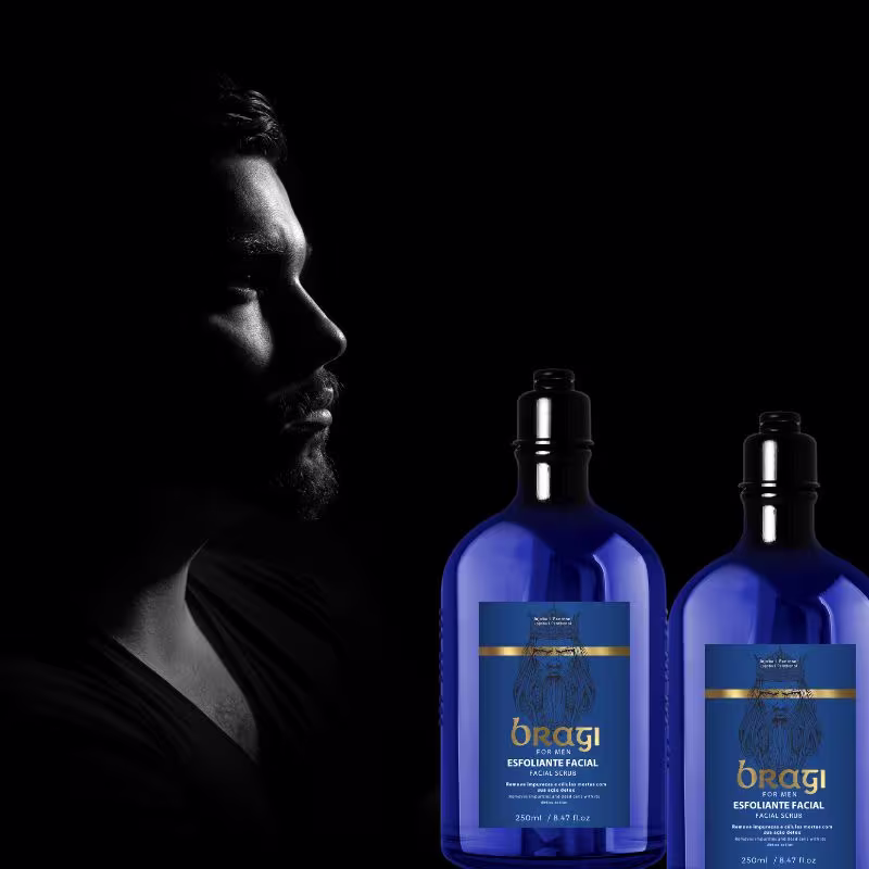 Em um fundo escuro, vemos o perfil de um homem com barba, cuja face é iluminada parcialmente. Ao lado dele, há duas garrafas azuis que exibem um rótulo com o nome do produto.