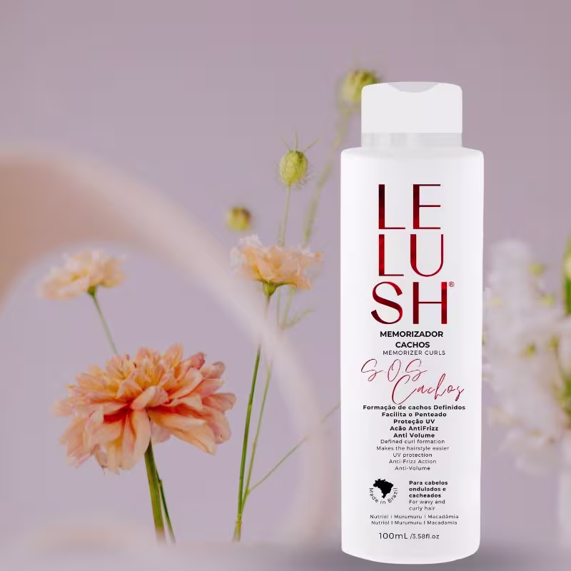 A imagem mostra a embalagem do memorizador capilar na frente de algumas flores desabrochadas em tons de amarelo e laranja, criando um cenário suave e natural para apresentar o produto.