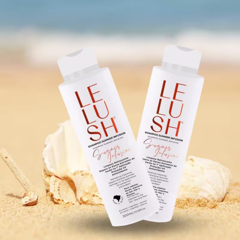 A imagem mostra dois frascos de shampoo brancos e têm o nome do produto escrito em letras alaranjadas. As embalagens estão posicionadas sobre uma areia clara em uma praia, cercados por algumas conchas marinhas.