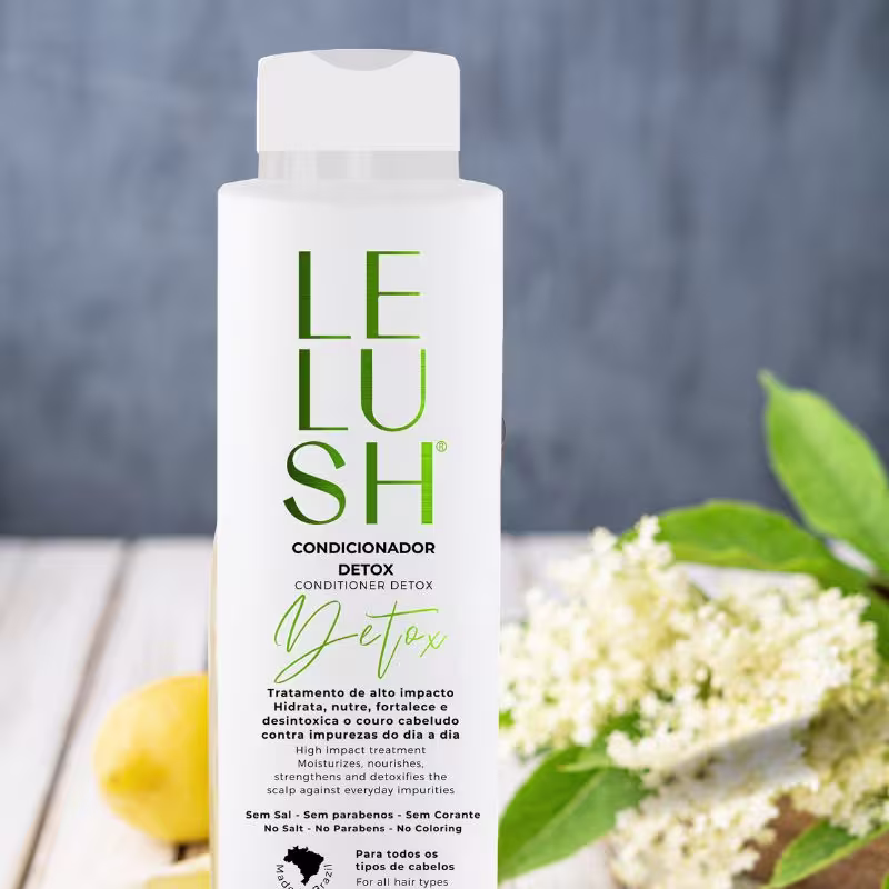 A imagem mostra um frasco de condicionador na cor branca com letras verdes formando o nome "Lelush". Ao lado do frasco, há uma flor branca e um limão, dando um toque natural à composição. A imagem transmite uma sensação de produtos naturais e veganos.