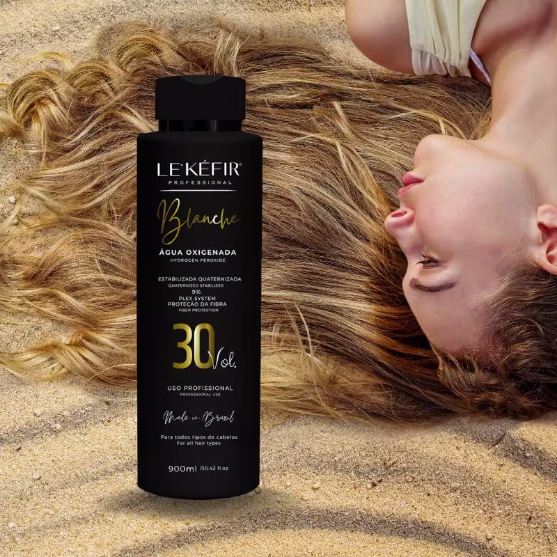 A imagem mostra o pote da água oxigenada posicionada junto a longos cabelos loiros espalhados, pertencentes a uma pessoa que não é totalmente visível na foto.