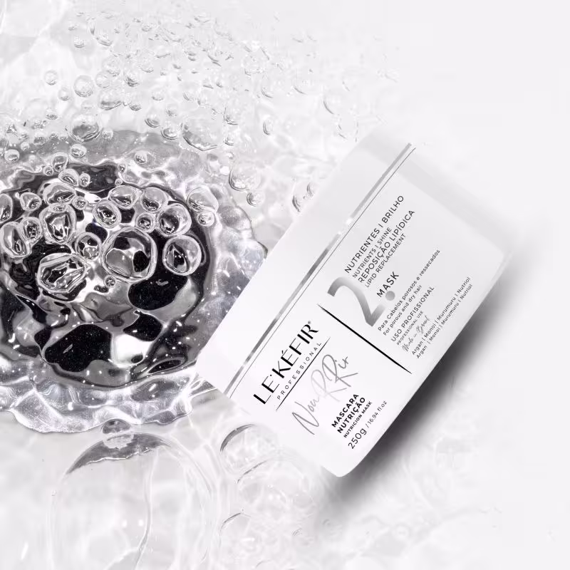 A imagem mostra a embalagem branca da máscara em destaque. Ao redor do frasco, há várias gotas de água formando uma textura borbulhante, sugerindo uma sensação refrescante e hidratante. A imagem transmite uma atmosfera bem clean.