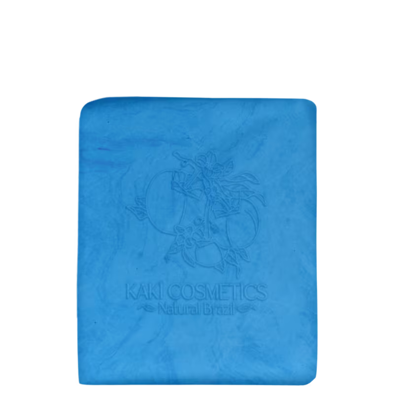 Barra de shampoo Kaki Cosmetics. A barra tem formato retangular e cor azul vibrante. Na superfície, há um desenho gravado em baixo relevo representando motivos florais estilizados. O logotipo da marca "Kaki Cosmetics" e a frase "Natural Brazil".