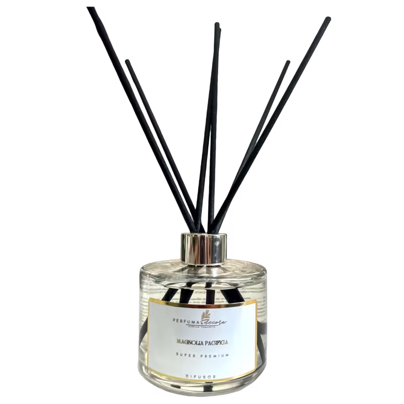 Difusor de aromas em frasco de vidro transparente. Contém hastes pretas que saem do bocal para difundir o aroma. Rótulo na parte frontal com o texto "Perfuma & Decora", "Magnolia Pacifica" e "Super Premium".
