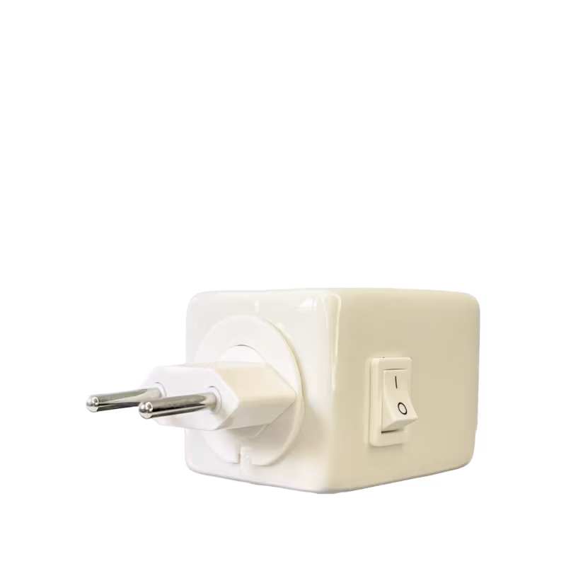 Difusor de ambiente de porcelana branco com um plugue de dois pinos. Possui um interruptor de ligar/desligar na lateral. O design é simples e retangular. Não há texto ou rótulos visíveis além do pequeno interruptor.