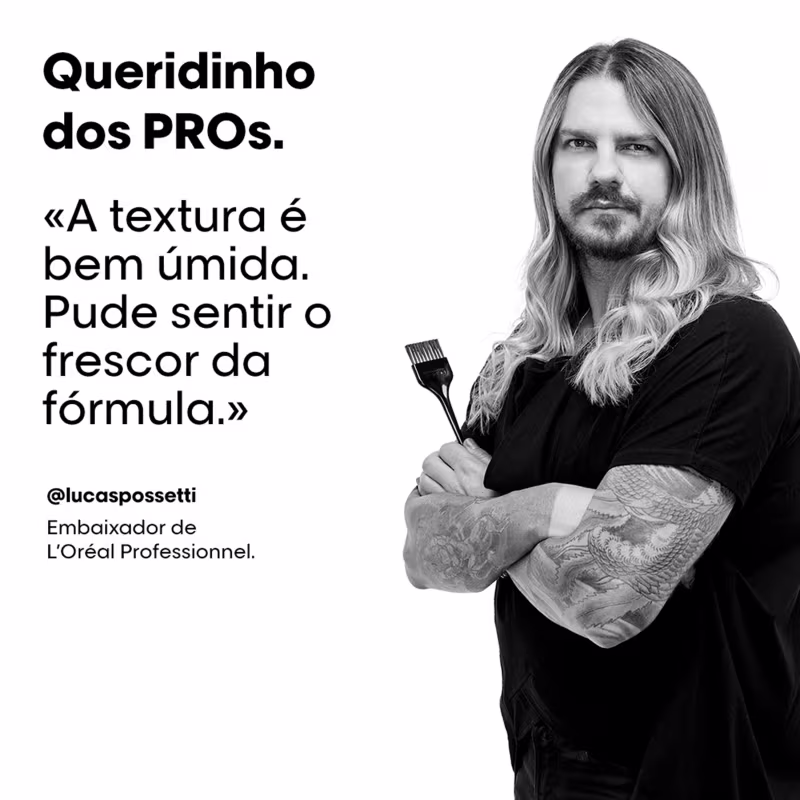 A imagem mostra um homem loiro de cabelos longos e barba, vestindo uma blusa preta. Ele segura um pincel de tinta. O texto destaca um depoimento dele sobre a textura e da fórmula de um produto da linha L'Oréal Professionnel, da qual ele é embaixador.
