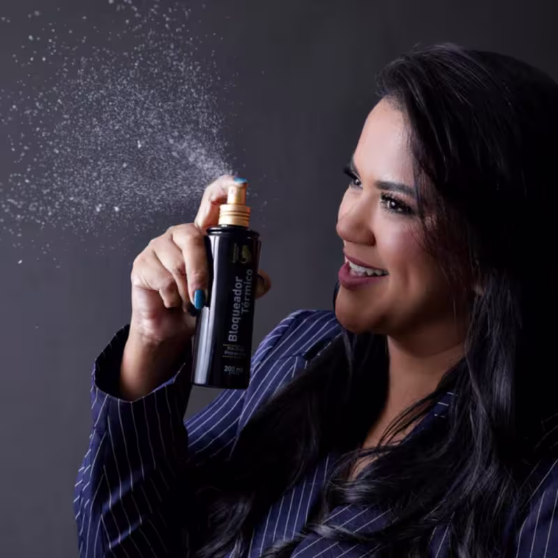 Produto de pré-chapinha. Frasco preto com detalhes dourados, contendo 200 ml de produto. O frasco é cilíndrico, com uma tampa dourada e uma câmara de vidro transparente na parte superior.