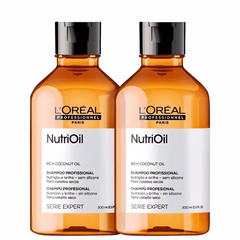 A imagem mostra dois frascos de shampoo da linha NutriOil da L'Oréal Professionnel. Os frascos são de plástico transparente âmbar com tampas pretas. O rótulo indica que o produto é enriquecido com óleo de coco rico e é destinado a cabelos secos.