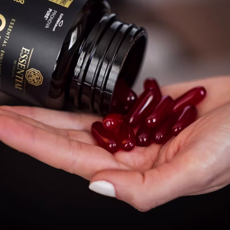 A imagem mostra as cápsulas sendo despejadas do frasco em uma mão.