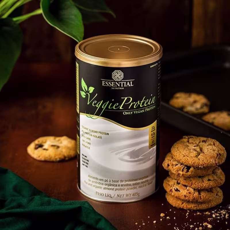 A imagem mostra uma lata de suplemento com rótulo preto e letras verdes e bege ao lado de cookies.