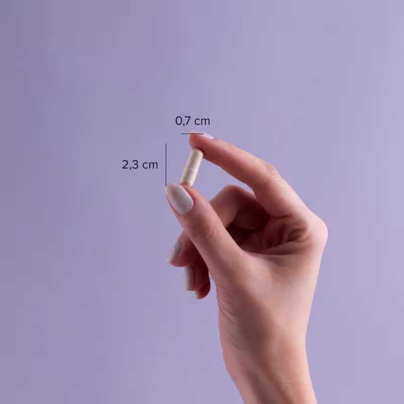 A imagem mostra uma mão segurando uma cápsula com o dedo polegar e o indicador, além de indicação de tamanho da cápsula: 0,7cm x 2,3cm.