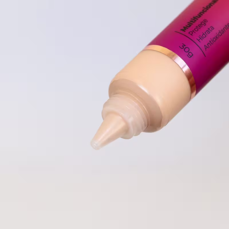 Base em tubo cilíndrico de plástico. A ponta do tubo mostra a cor bege claro da base. O tubo tem uma faixa dourada próxima à ponta.