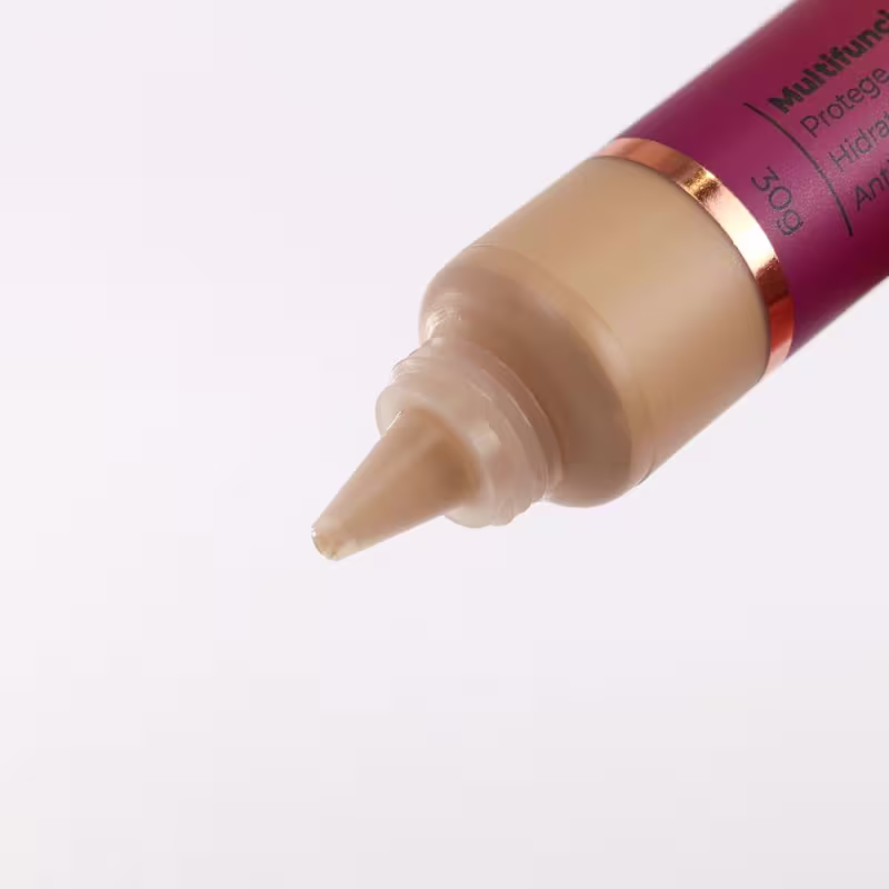 Base em tubo cilíndrico de plástico. A ponta do tubo mostra a cor bege médio da base. O tubo tem uma faixa dourada próxima à ponta.