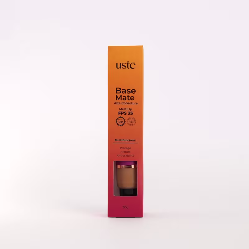 Base Mate em embalagem retangular laranja. Rótulo preto com o nome do produto "Base Mate" e informações como "MultiUp FPS 35", "Multifuncional", "Protege, Hidrata, Antioxidante". Pequena janela mostra o produto a cor marrom escura da base.