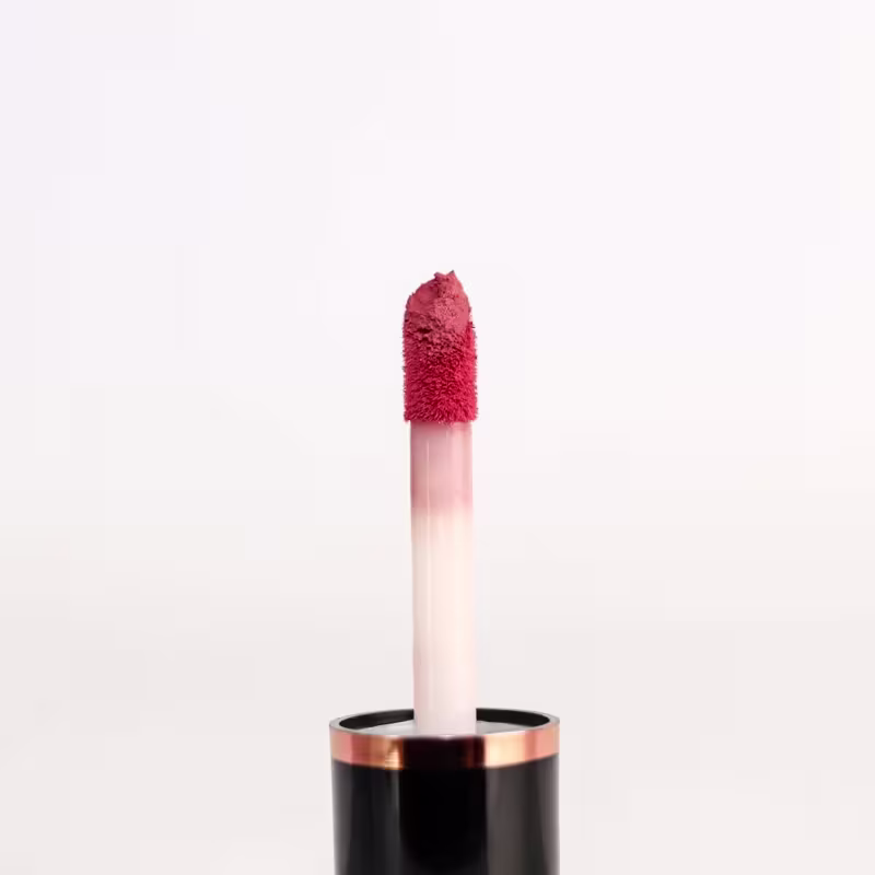 Pincel do batom com cabo curto e fino de cor rosa. A ponta é arredondada e coberta por fibras sintéticas felpudas.