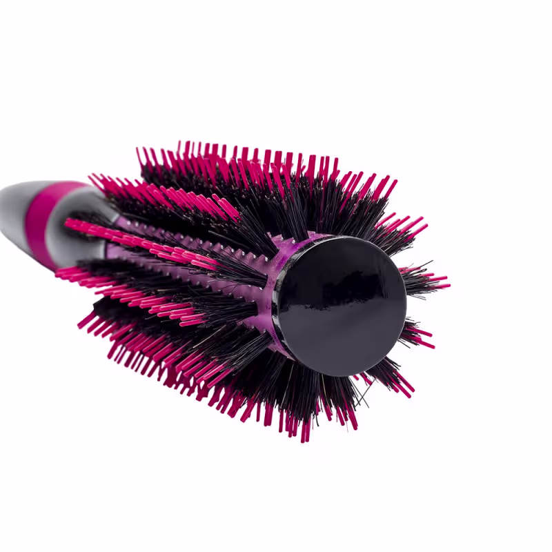 A imagem mostra a escova de cabelo em formato arredondado. Ela possui um corpo preto com cerdas rígidas e densas em tons de rosa vibrante e preto. Design moderno e ergonômico com cabo emborrachado rosa.