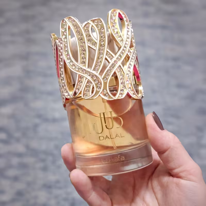 Frasco de perfume Lattafa Dalal com tampa dourada decorada com cristais brilhantes em um design intrincado, apresentando o logotipo da marca em destaque.