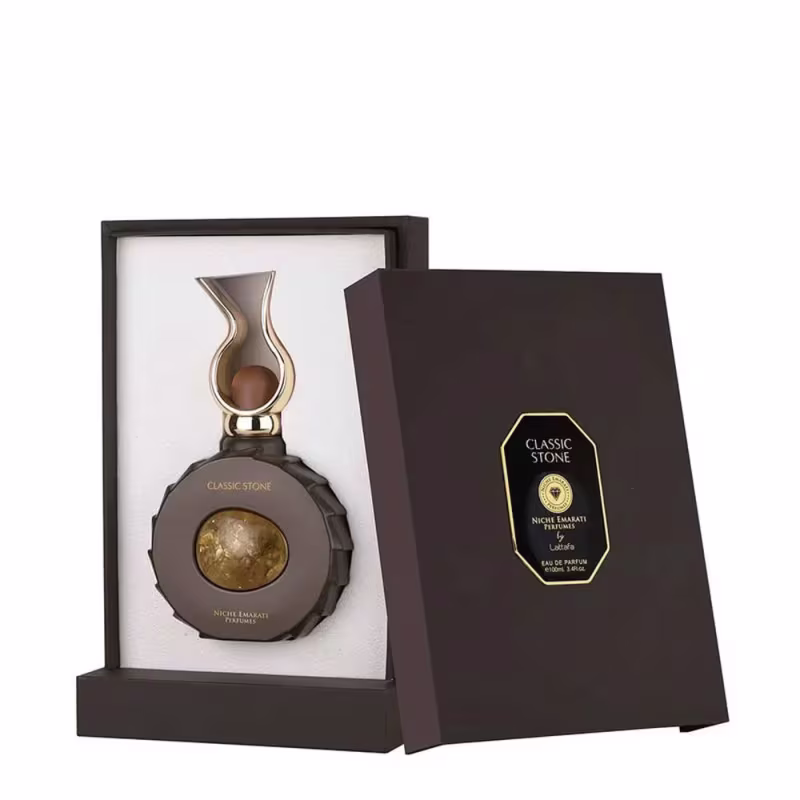 Perfume da marca Lattafa Perfumes, com frasco de vidro em formato diferenciado e caixa preta com detalhes dourados. O produto é chamado de "Classic Stone" e apresenta uma pedra dourada em destaque.