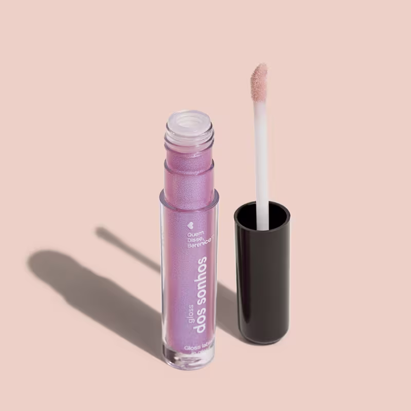 A imagem mostra o frasco do gloss labial e ao lado há um aplicador de espuma na cor branca com a ponta no tom furtacor e base preta.