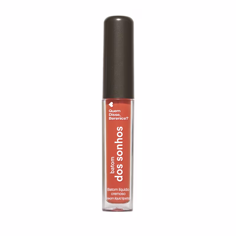 A imagem mostra um batom labial em uma embalagem cilíndrica com a tampa preta e o tubo transparente permite ver o tom laranja brilhante do batom e a marca Quem disse, Berenice? e a linha estampados no frasco.