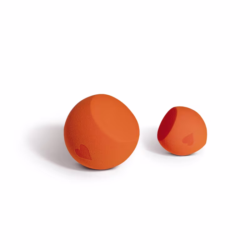 Dois objetos esféricos de cor laranja, com um coração vermelho impresso em um deles. São produtos de beleza da marca Quem Disse, Berenice?