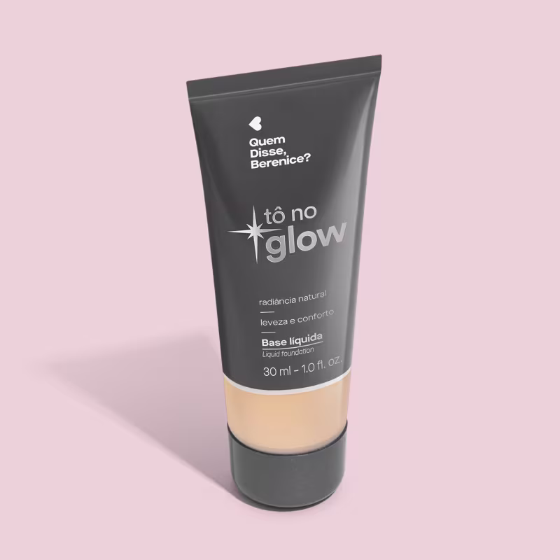 O produto apresentado é uma base líquida da marca Tô no Glow, com embalagem em tubo plástico preto e branco. O rótulo exibe o nome da marca e a descrição "Radiância natural, leveza e conforto". O produto é classificado como "Base líquida".