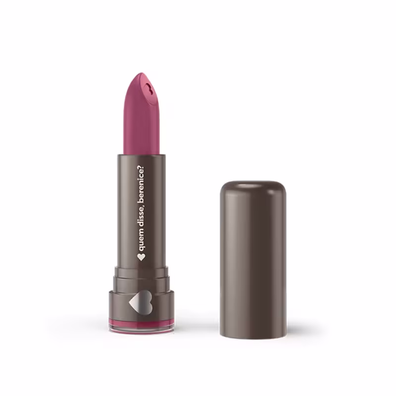 Um item de perfumaria rosa em formato de batom com embalagem metálica cinza. O rótulo exibe o texto "Quem Disse, Berenice?" em letras brancas.