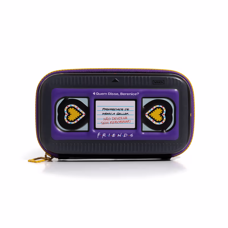 Acessório com design inspirado na série de TV "Friends". Imita fita VHS com uma mensagem sobre não devolver algo sem recarregar. Possui detalhes em roxo e amarelo, com ícones de coração em ambos os lados.