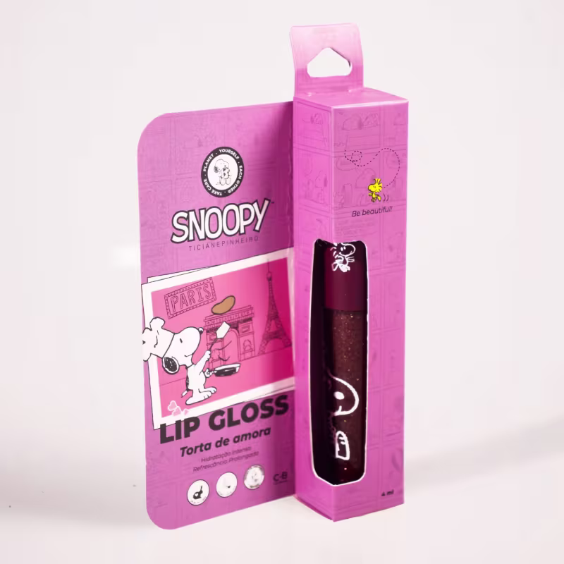 A caixa possui informações sobre o produto, indicando que se trata de um "Lip Gloss" com o nome "Torta de amora". O brilho labial em si é de cor escura, provavelmente de tonalidade roxa ou vinho.