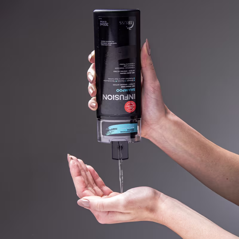 Uma mão segura a garrafa de shampoo e despeja um pouco do produto em outra mão